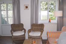 Klönecke in der modernen hellen, weiß-grauen Wohnung mit orangenem Sonnenkuss.
